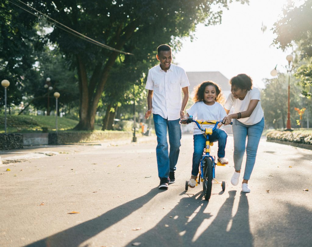 parents teaching a child to ride a bike